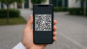 Eine Hand hält ein Smartphone. Auf dem Bildschirm ist ein QR Code zu sehen.