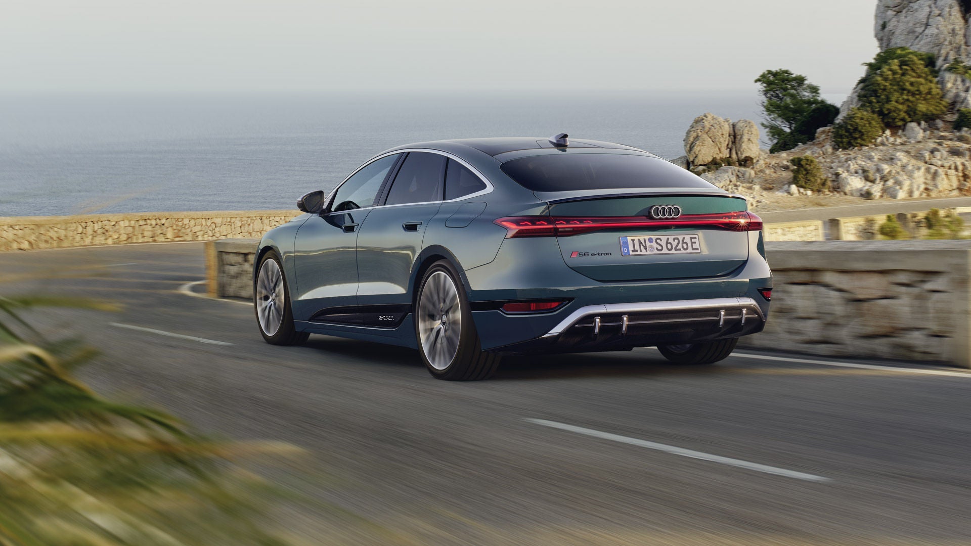 Der S6 Sportback e-tron im schrägen Heckprofil, während er eine kurvige Küstenstraße entlangfährt.