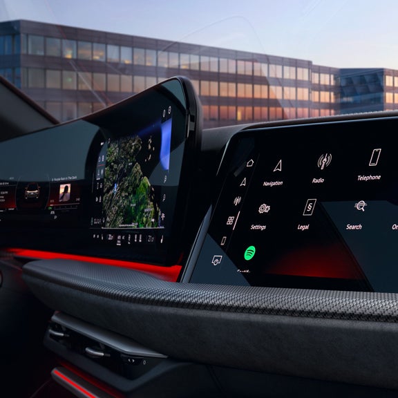 Car dashboard with touchscreen display showing various icons including navigation and music apps.