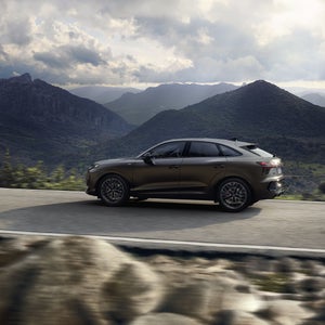 Der Q3 Sportback fährt auf einer Landstraße in einer bergigen Landschaft.