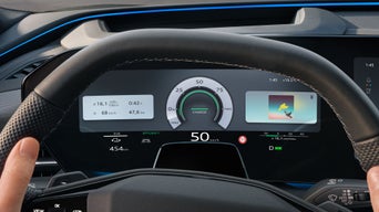 Close-up of the steering wheel and the driver's display behind it while driving.