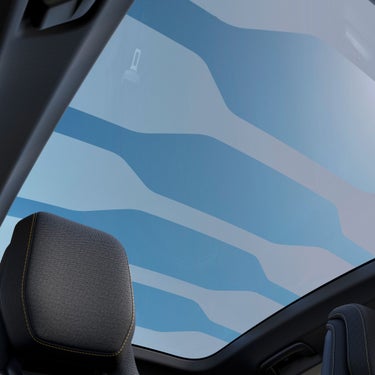 View from inside a car, showcasing a panoramic sunroof with wavy blue patterns against a clear sky backdrop.