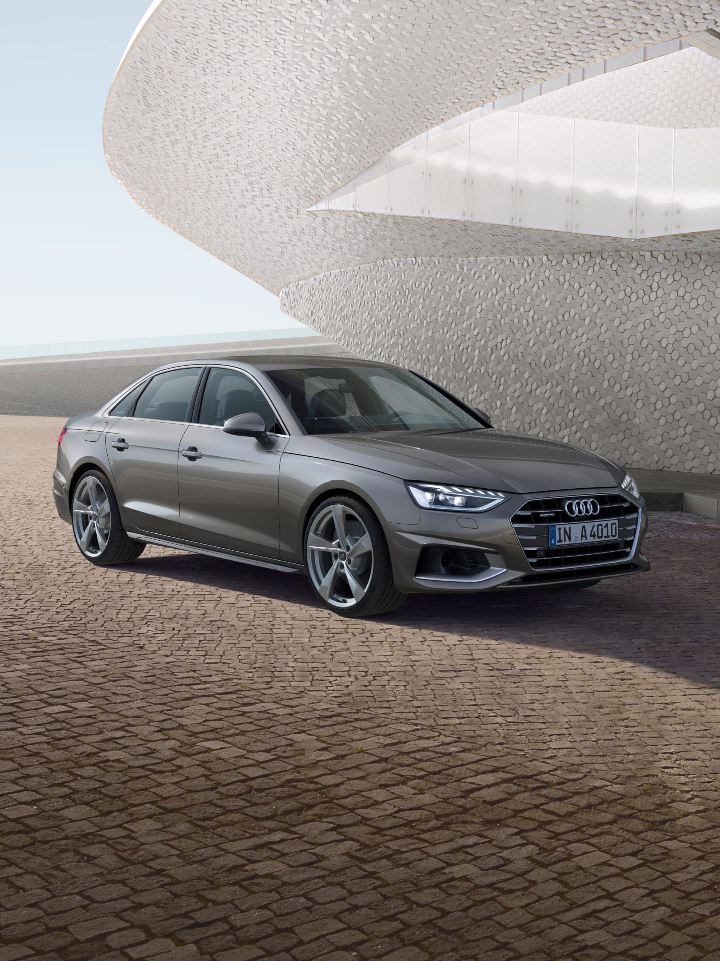 A silver Audi A4 Saloon parked outside a modern building with hexagonal facade patterns.