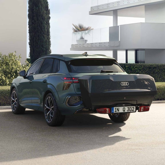 Rear view of a Q3 SUV with black rear box, parked in front of a modern house.