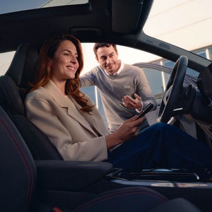 A woman sitting in a car while a man is talking to her