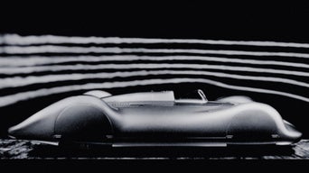 Side view of a fully clad, historic Audi racing car against a dark background. Streamlines are indicated above the vehicle.