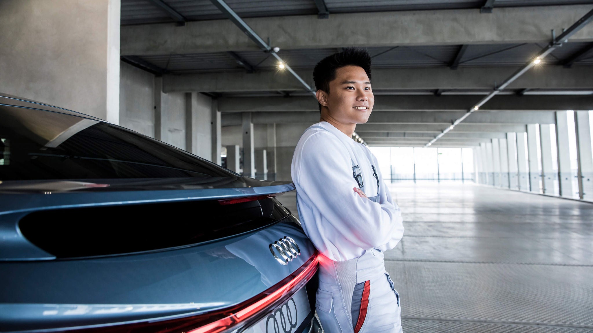 Junger Mann lehnt entspannt am Heck eines Audi