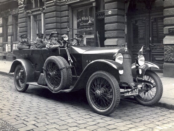 Black and white photo of several people in the Audi Type C Alpine Champion in front of a shop