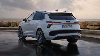 Ein weißer Q3 SUV e-hybrid von hinten fährt auf nasser Straße entlang der Küste.
