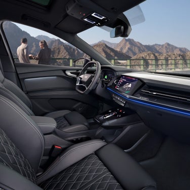 Car interior with leather seats and dashboard, overlooking mountain scenery.