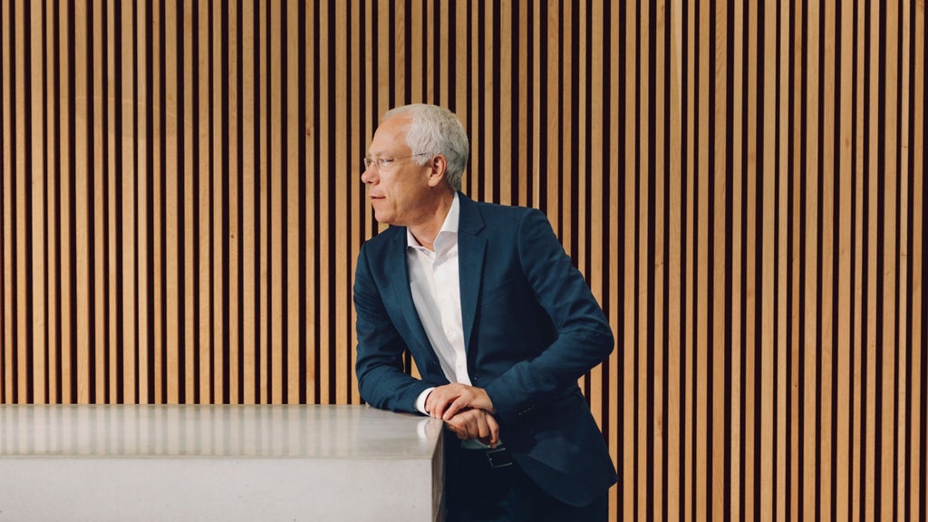 Peter Gladbach is standing at his desk, looking out of the window.