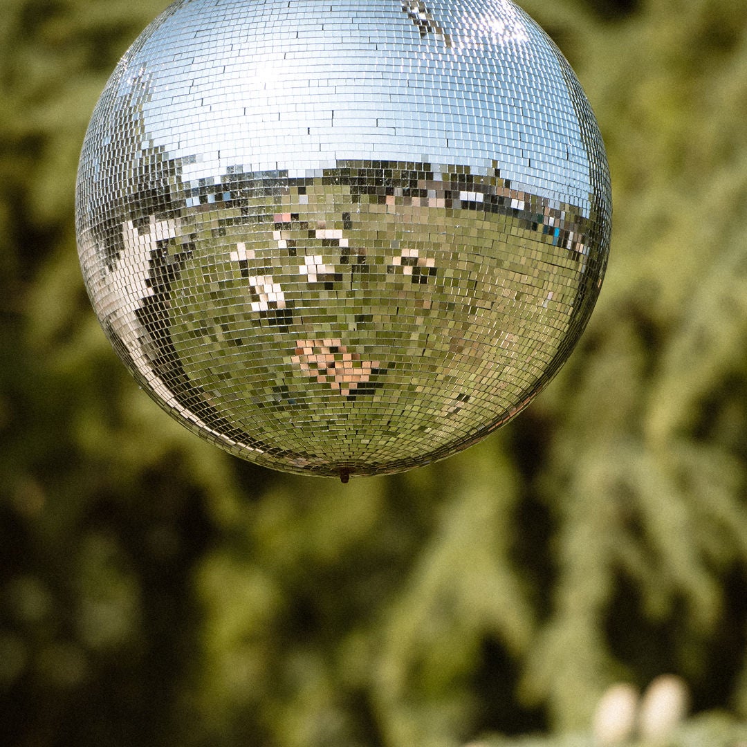 mirror sphere in the woods reflecting the sky and woodland green surroundings