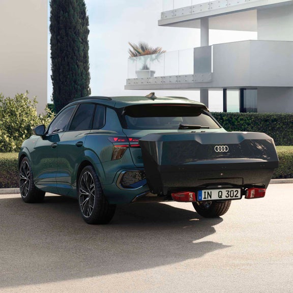 Vista trasera de un Q3 SUV con caja trasera negra, aparcado delante de una casa moderna.