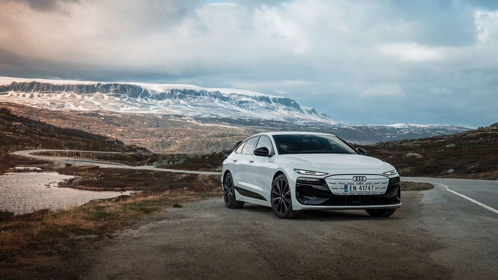 White Audi A6 Sportback e-tron in front of a Scandinavian natural backdrop with coniferous forests, snow-covered mountains and a river.