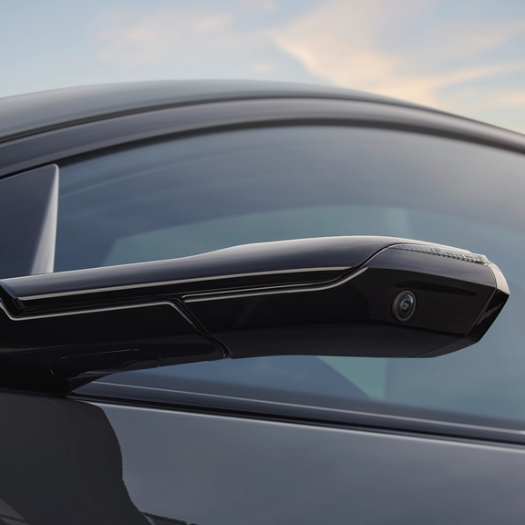 An Audi electric vehicle driving on a scenic mountain road at sunset