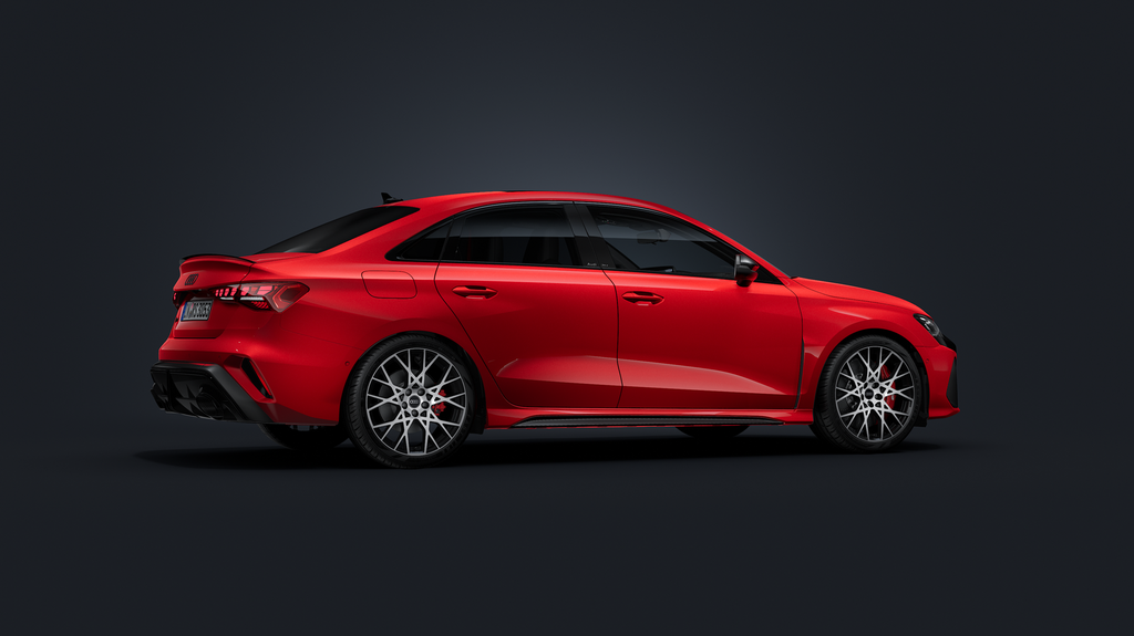 De Audi RS 3 Berline, van opzij gezien tegen een donkere achtergrond.