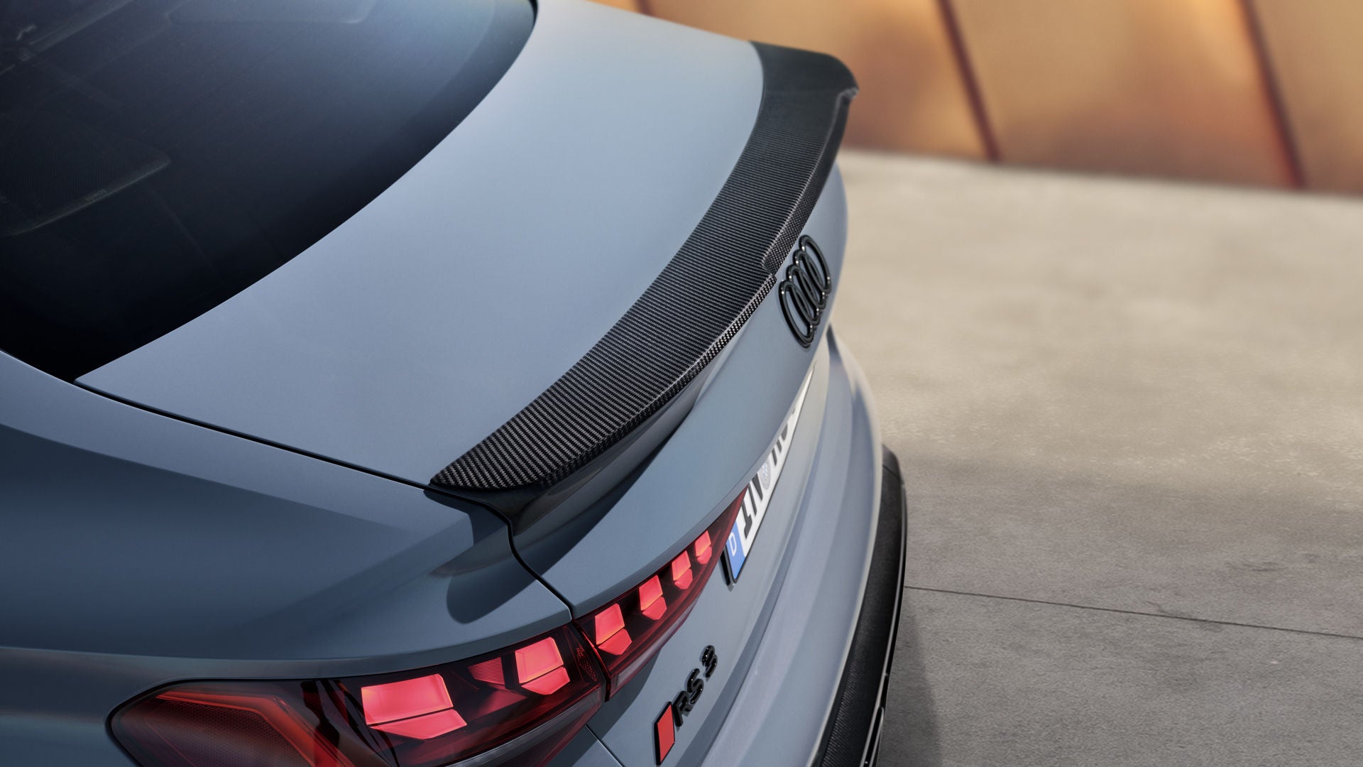 Zicht op de achterkant van de Audi RS 3 Berline, met focus op de achterklepspoiler in carbon.