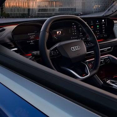 Interior view of an Audi vehicle's steering wheel and digital dashboards.