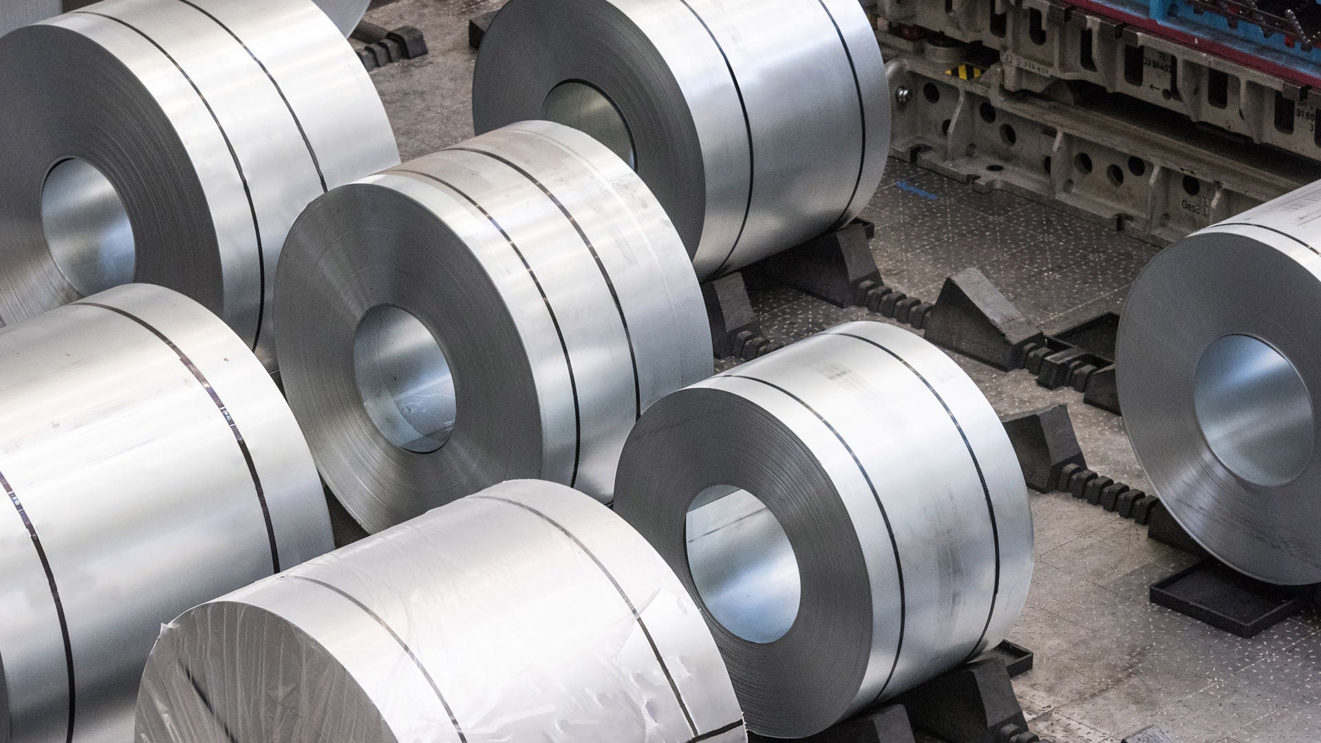 A number of large metal coils lie next to each other on brackets in the press shop at the Audi plant in Neckarsulm.