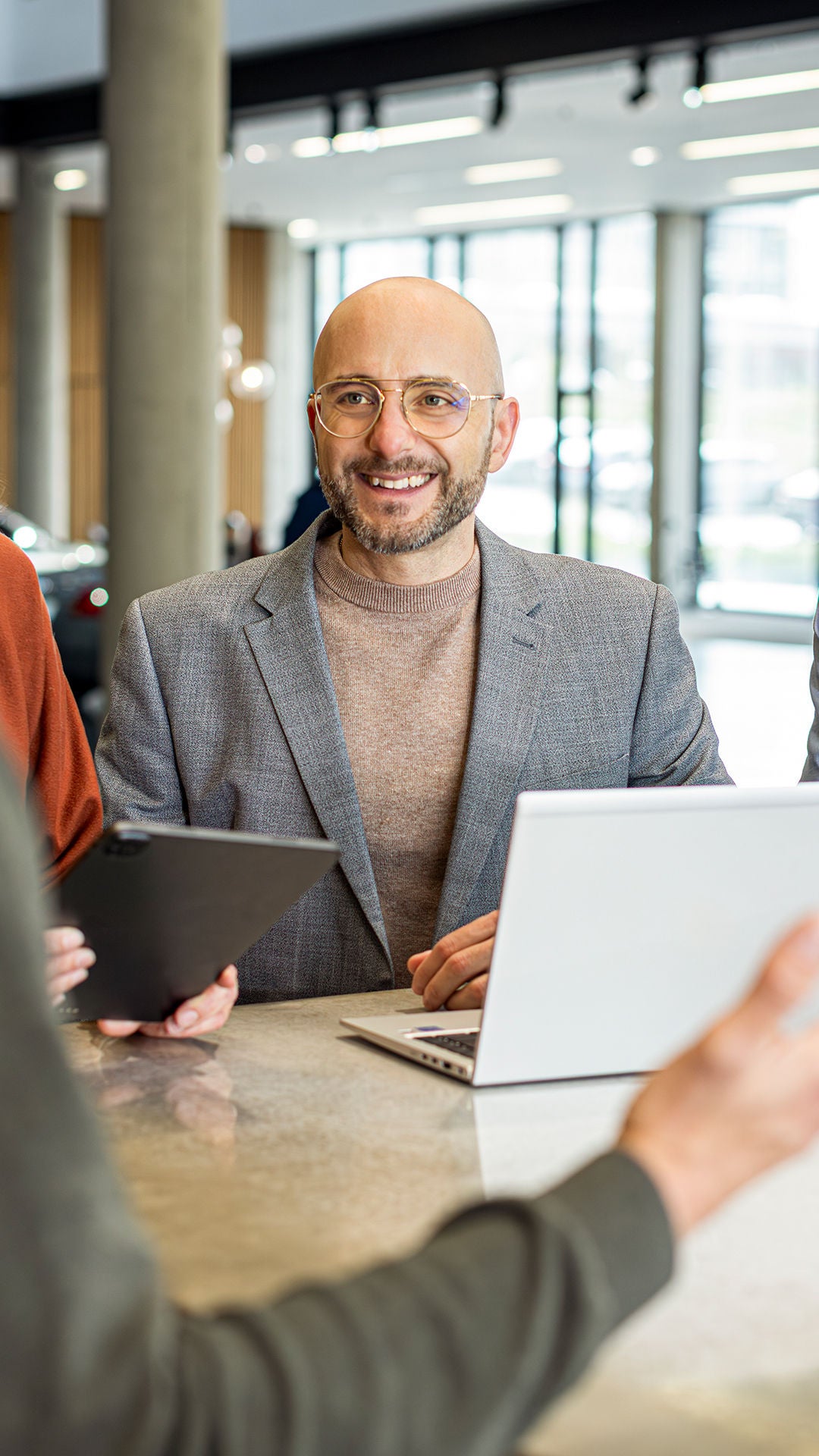 Mario De Felice steht mit ein paar Kollegen an einem Tisch worauf ein Laptop steht und lacht