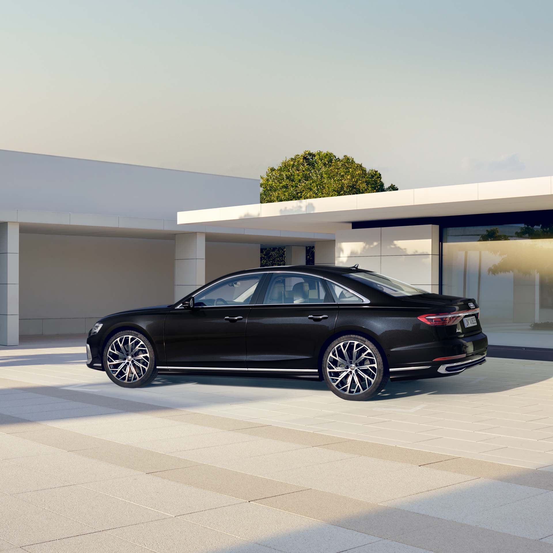 Schwarzer Audi A8 steht vor einem modernen, hellen Gebäude bei Tageslicht.