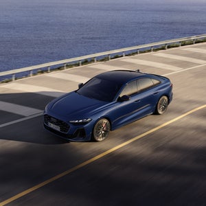 Die S5 Limousine von schräg oben. Sie fährt auf einer Straße entlang der Küste.