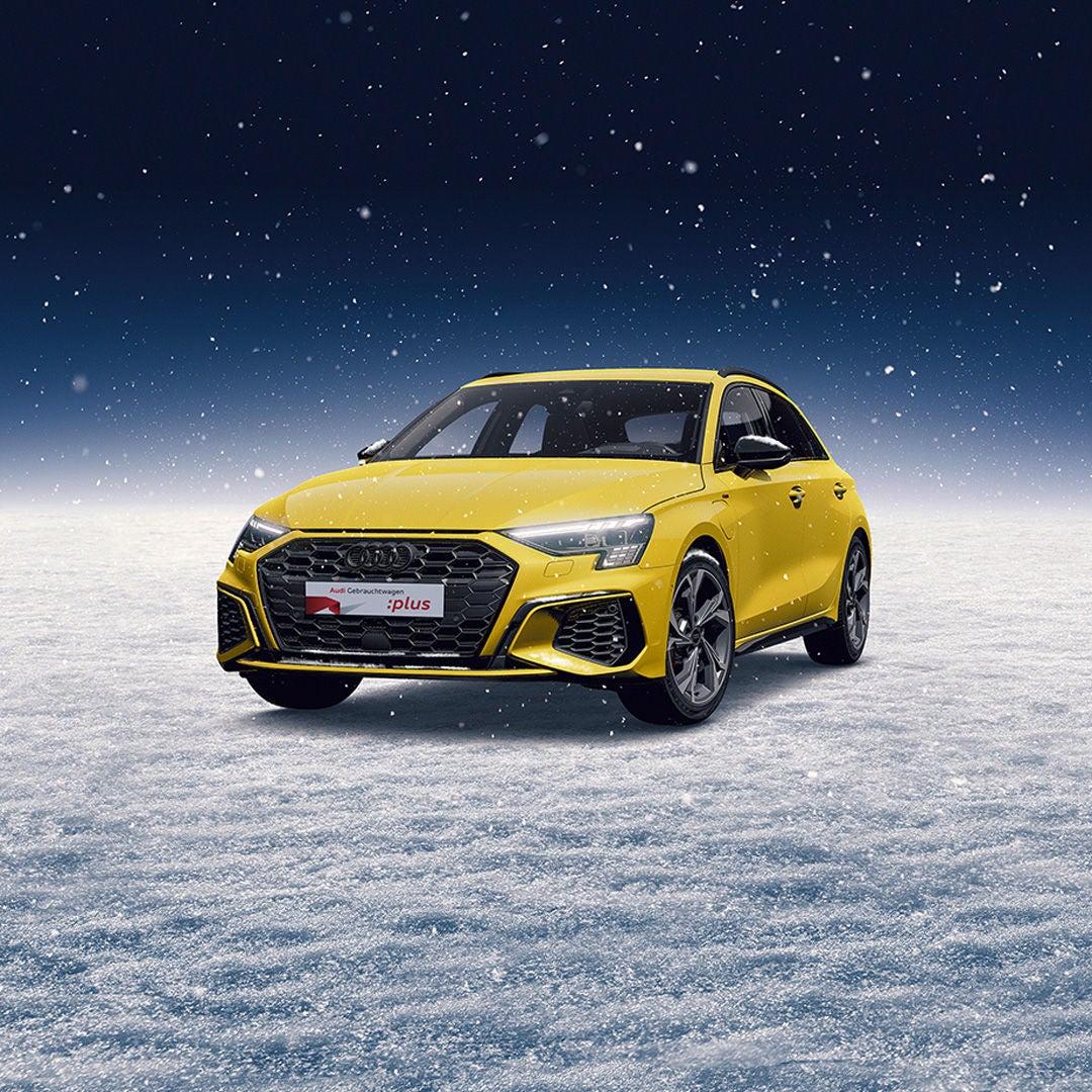 Ein gelber Audi A3 steht auf einem schneebedeckten Untergrund, während es schneit.