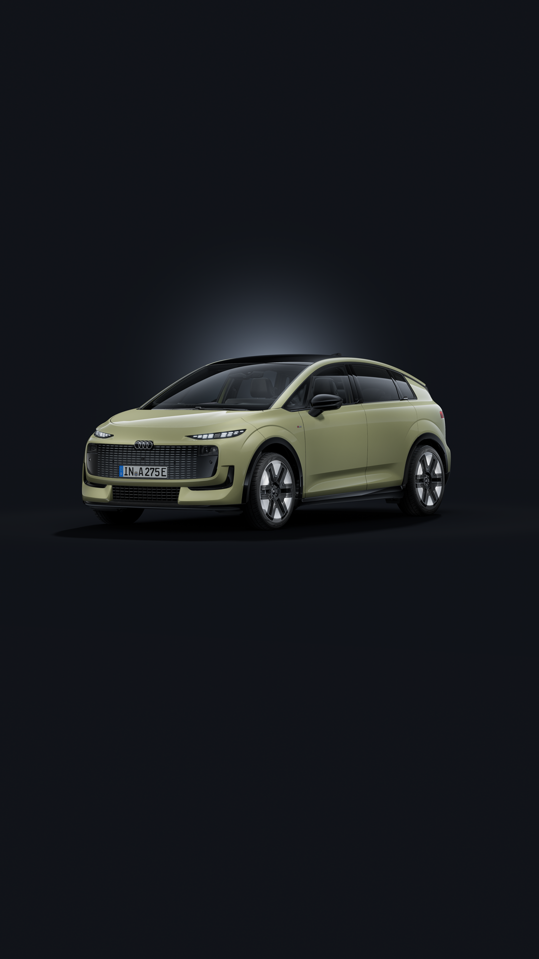 Der Audi A2 e-tron, fotografiert von der Seite, parkt vor einem modernen Gebäude in urbaner Umgebung. Das schräg einfallende Sonnenlicht taucht die Szenerie teilweise in Schatten.