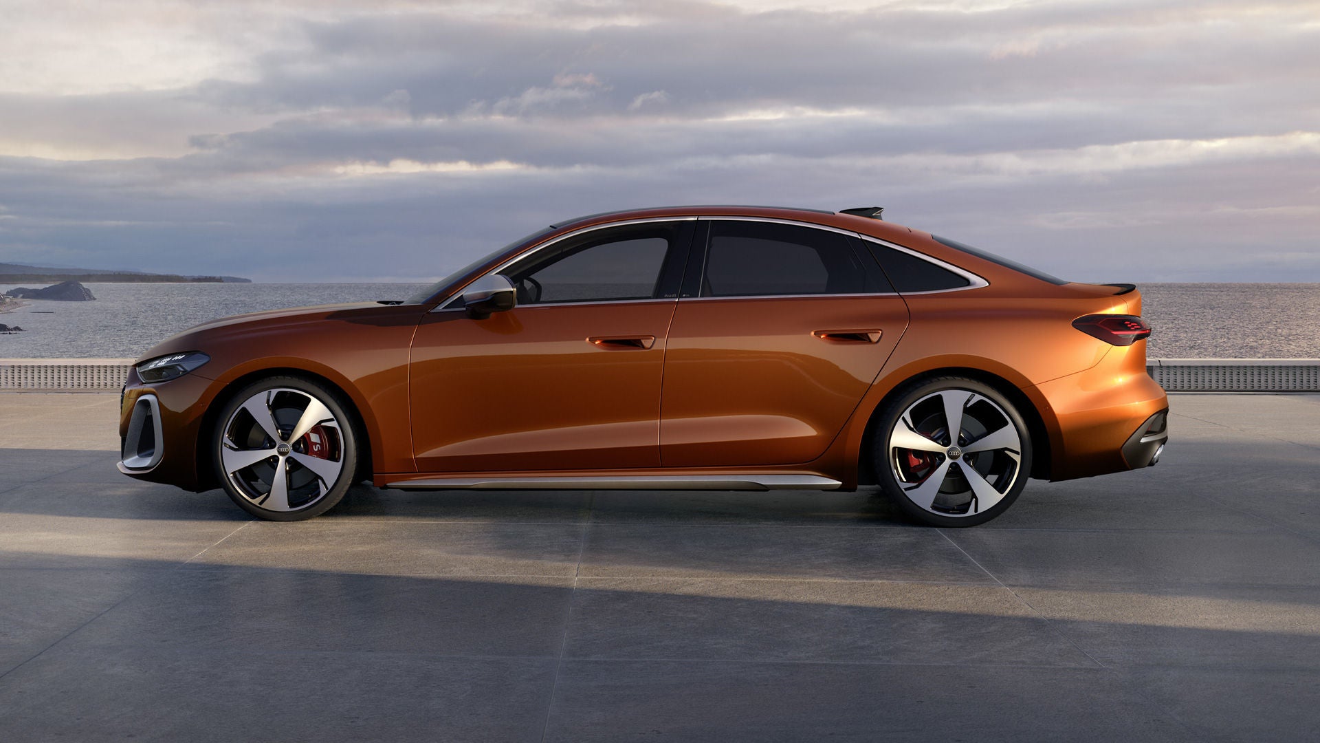 Die S5 Limousine steht im Seitenprofil auf einer Promenade an der Küste. Das Fahrzeug ist in Ipanemabraun Metallic lackiert.