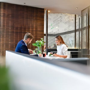 Mann und Frau essen an einem Tisch im Restaurant; Salat und Getränke, moderne Innenausstattung im Hintergrund.