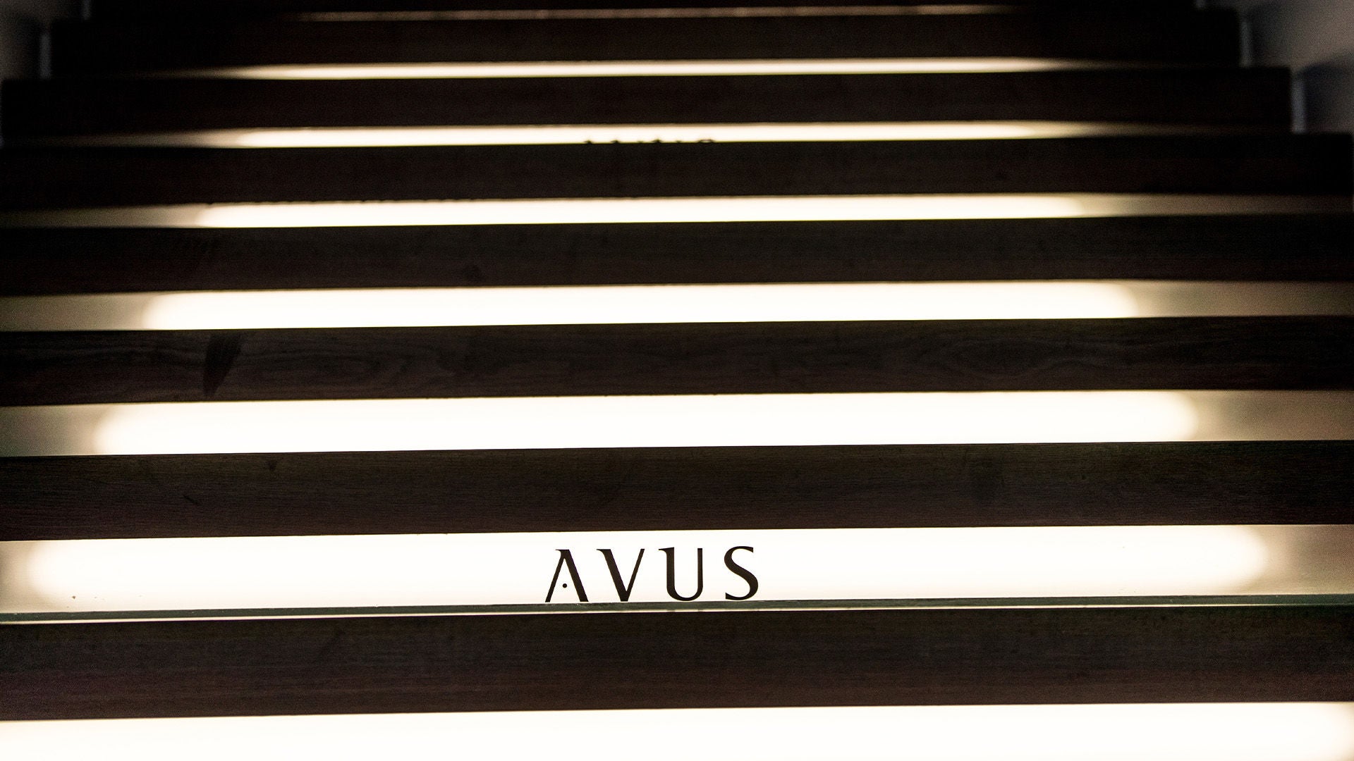 Illuminated steps with the lettering “AVUS” in dark surroundings.