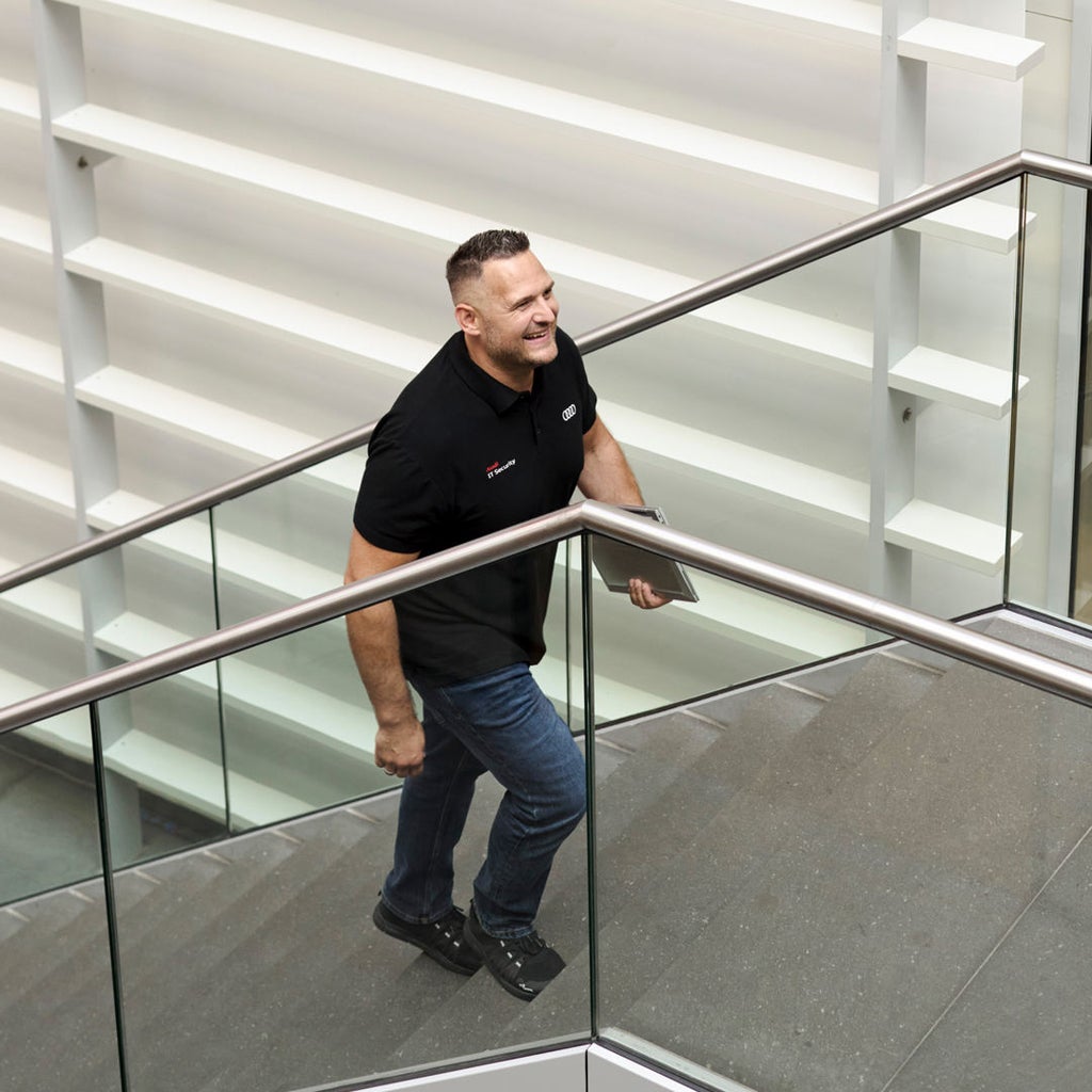 Andreas Walter hält einen Laptop in der Hand und geht eine Treppe hoch.