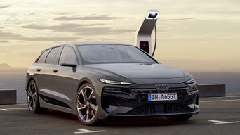 A6 Avant e-tron er tilkoblet en ladestasjon på en parkeringsplass. Hav og fjell er synlige i bakgrunnen.&nbsp;