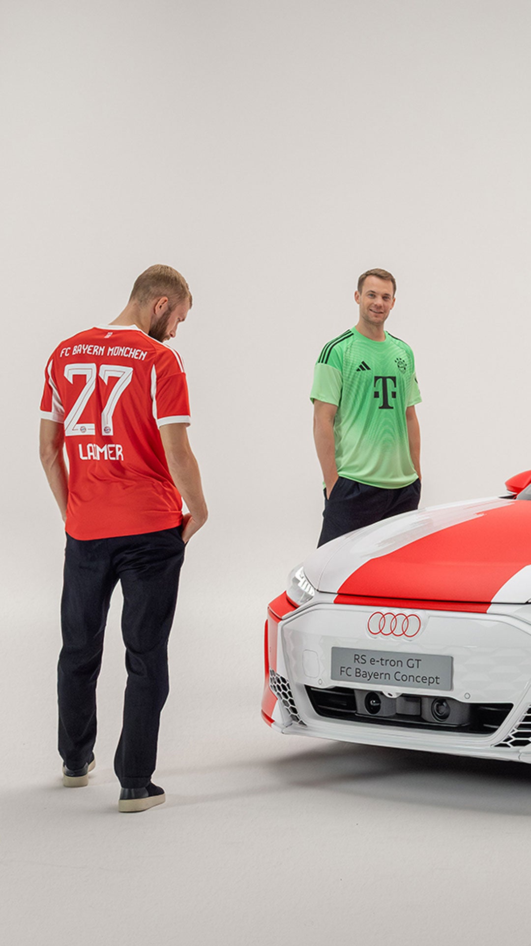 Drei Fußballspieler vom FC Bayern München stehen um einen rot-weißen RS e-tron GT herum