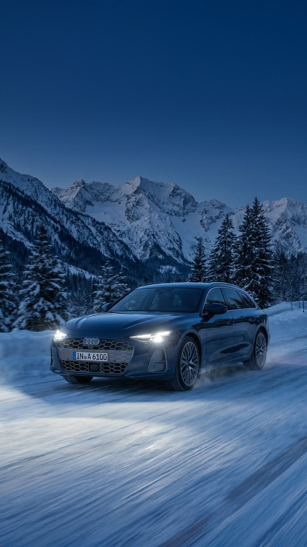 Ein dunkelblauer Audi A6 Avant fährt mit eingeschalteten Matrix LED Scheinwerfern auf einer verschneiten Straße durch eine winterliche Berglandschaft.