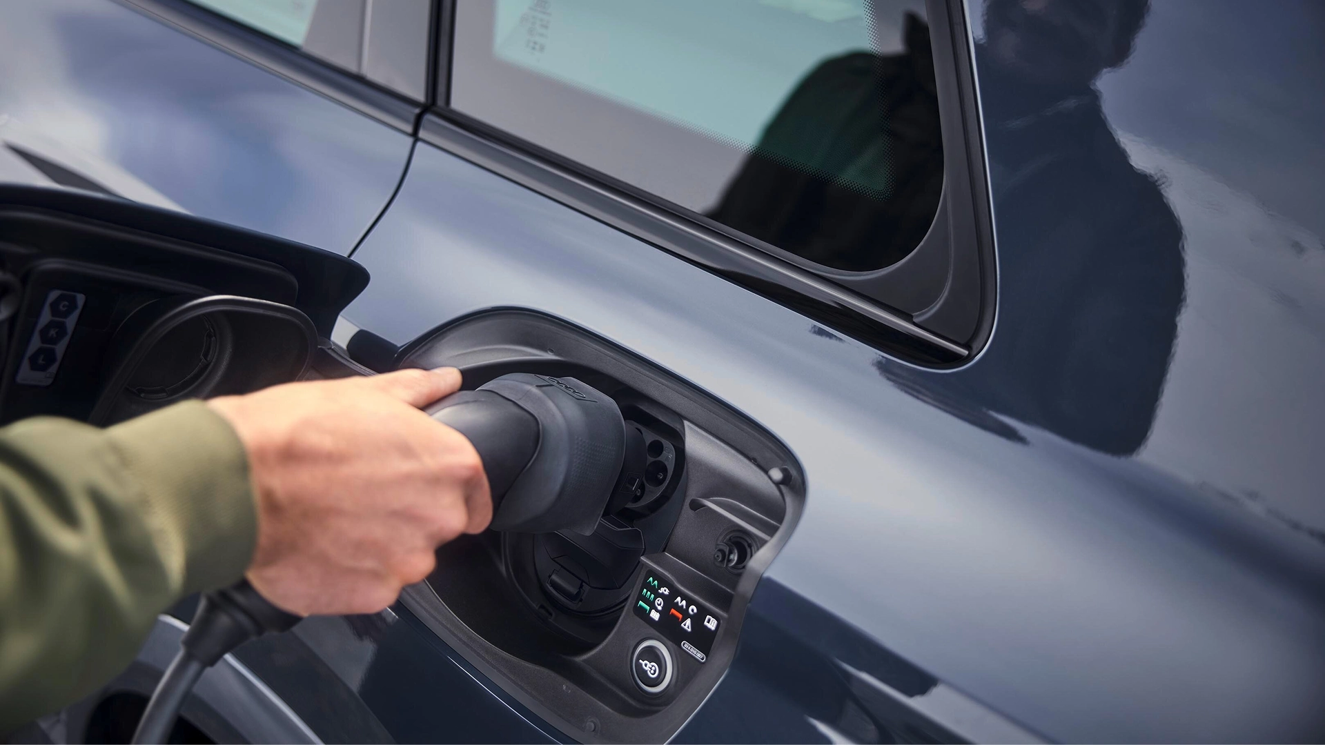 A charging station with a cable is located in front of a modern house.