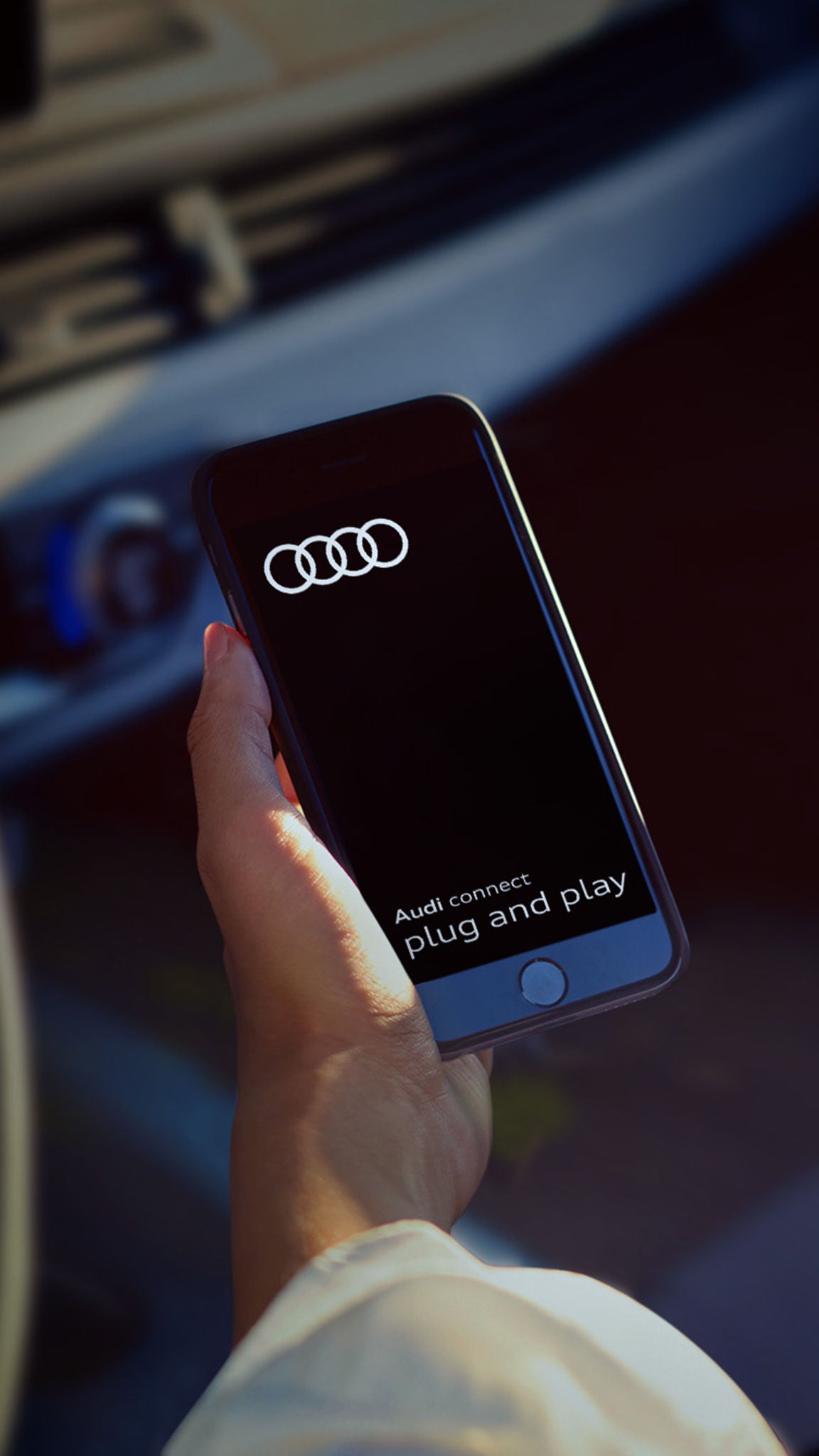 En kvinnas hand som håller en mobiltelefon som visar Audi Connect plug and play