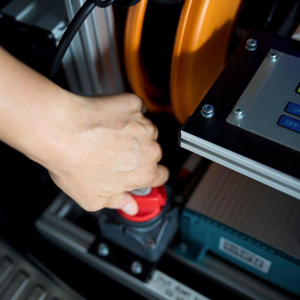 Eine Hand dreht an einem roten Knopf