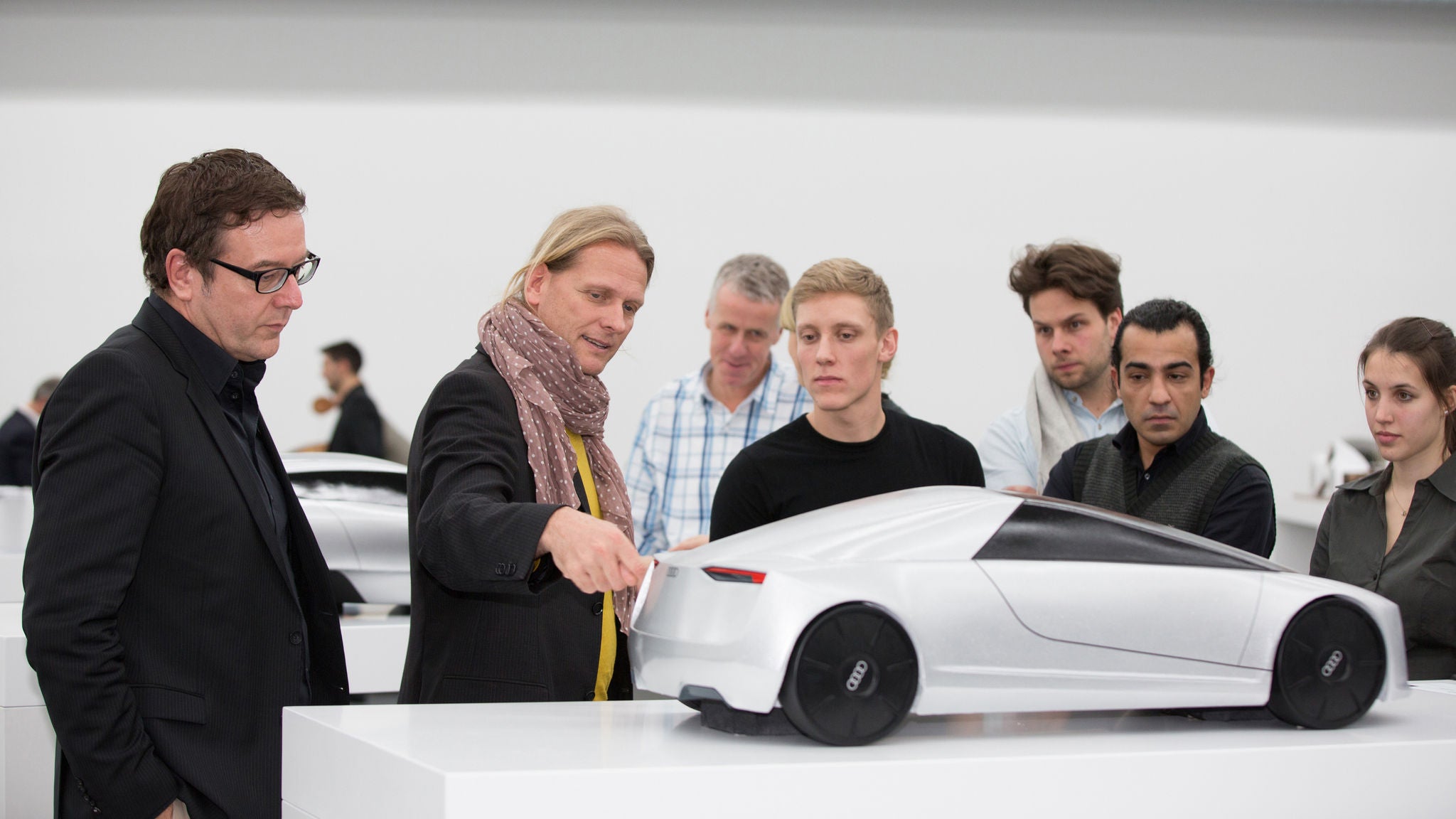 Sju personer som tittar på en Audi i miniatyr.