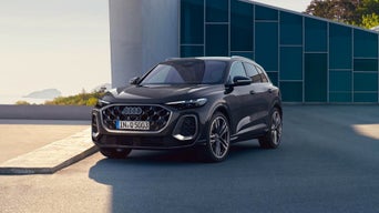 Side view of the Q5 SUV in anthracite in front of a modern building on the coast.