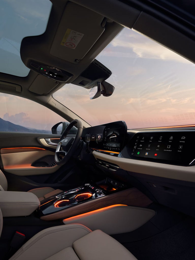 Beleuchteter Innenraum der Audi A5 Limousine mit digitalen Displays und Ambiente-Licht bei Sonnenuntergang.