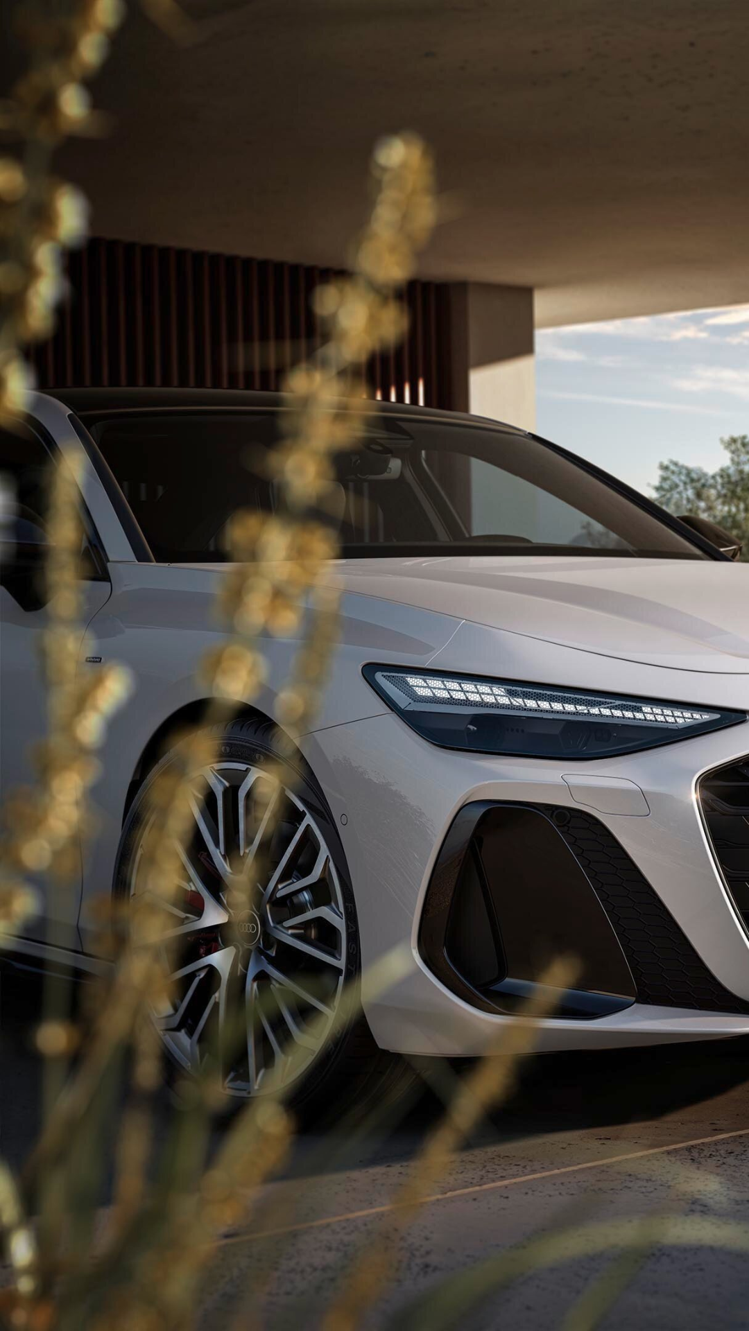 White Audi car parked in front of Autumn flowery with matrix LED headlights on