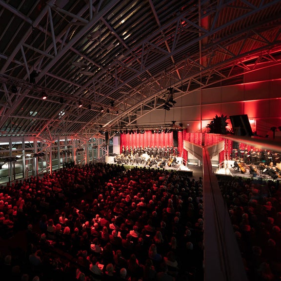 Festliche Bühne mit Musikern, davor ein vollbesetzter Saal mit Zuschauen.