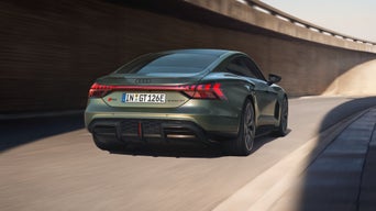 Grüner Audi RS e-tron GT performance von hinten auf einer kurvigen Straße unter einer Betonbrücke.