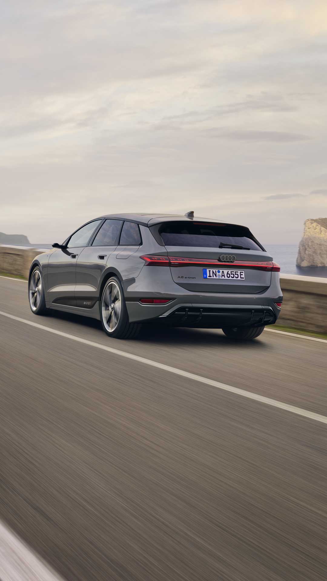 A6 Avant e-tron som kjører på en kystvei sett skrått bakfra. Fjell og klipper er synlige i bakgrunnen.&nbsp;