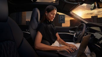 Eine Frau arbeitet im Auto am Laptop