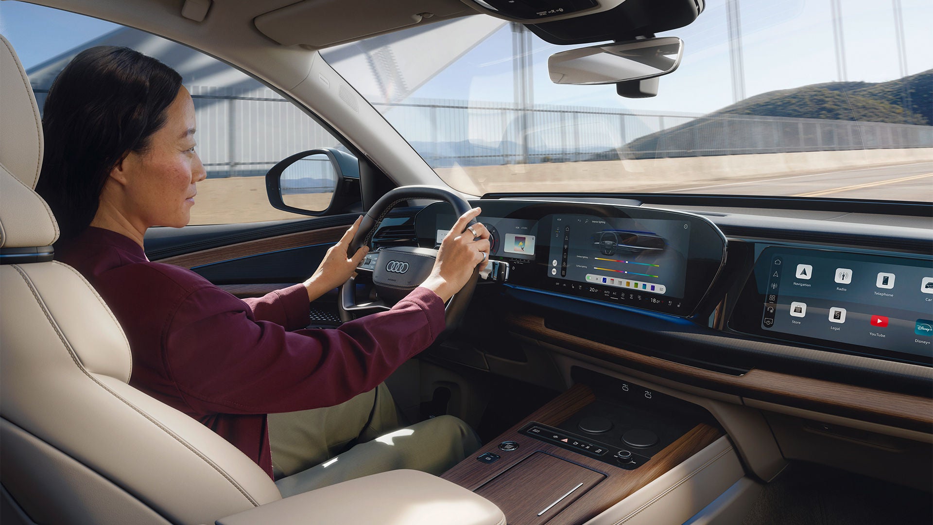 Conducteur au volant d'une Audi Q7, les yeux rivés sur la route, devant un écran numérique.
