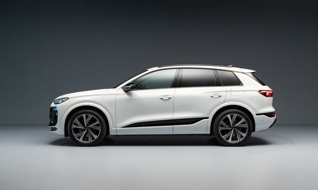 Seitenansicht eines weißen Audi SQ6 SUV e-tron. Er steht vor einem dunklen Hintergrund.