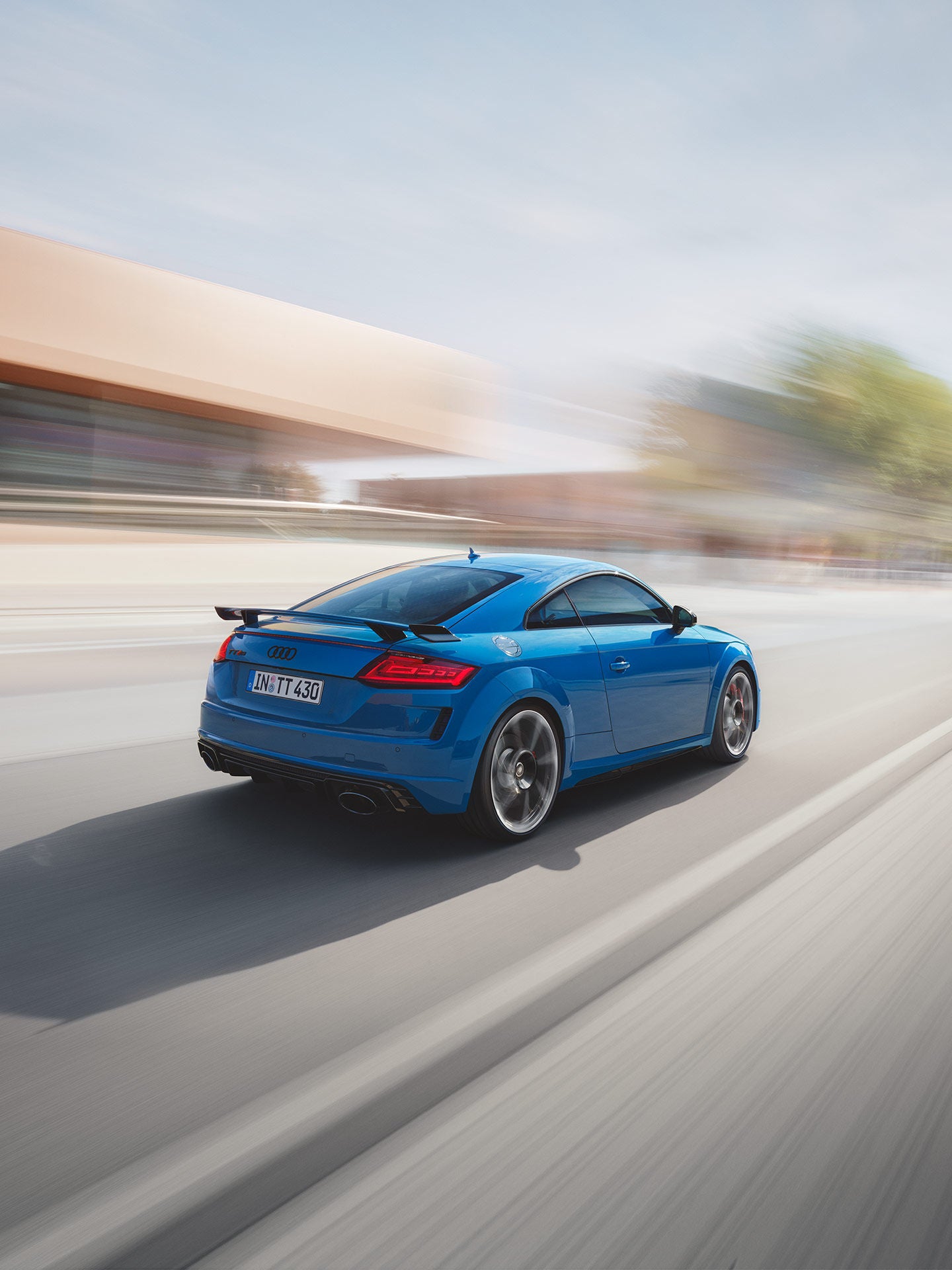 Blue Audi TT moving at speed on an open road with blurred background.