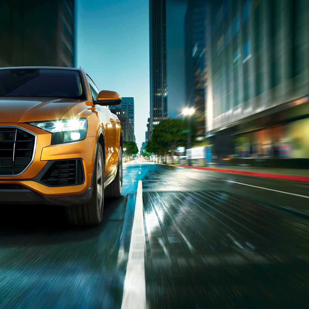 Närbild på framsidan av en gulbil i stadsmiljö.